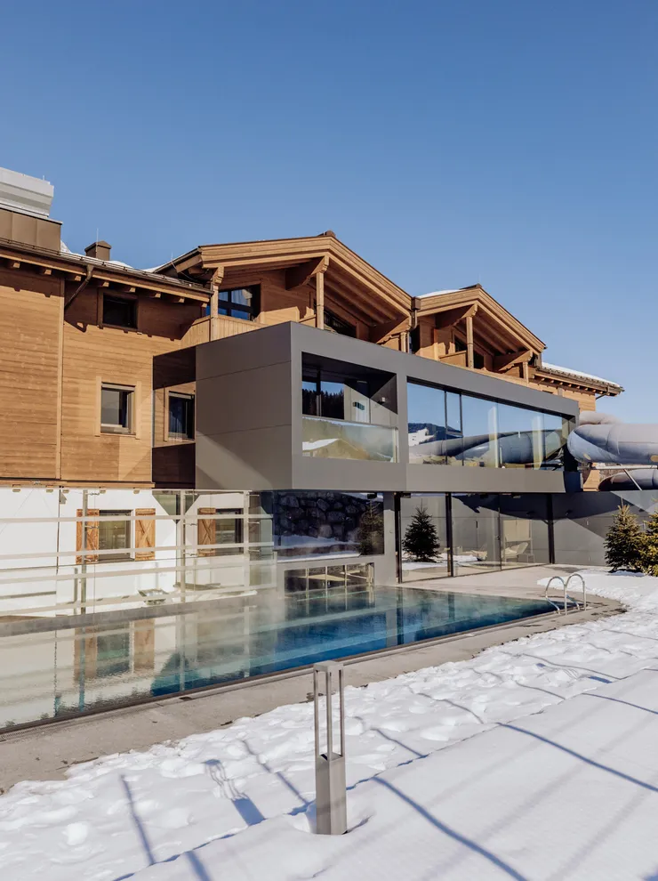 Luxury mountain hotel with outdoor pool in snowy alpine landscape