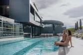 Couple relaxing by the edge of a modern outdoor hotel pool with mountain view