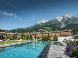 Outdoor luxury pool with mountain view and landscaped garden at alpine wellness resort