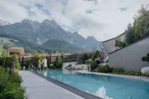 Couple walking by outdoor wellness pool with mountain view at luxury alpine resort