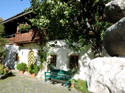 Traditionelles Alpenhaus mit Holzbalkon, Blumentöpfen und Kopfsteinpflasterhof