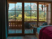 Cozy hotel room with mountain view through wooden balcony window in alpine region