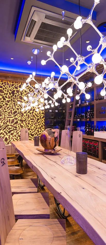 Moderner Weinkeller mit Holztisch, Designerbeleuchtung und beleuchteten Weinregalen