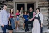 Family in traditional clothing standing in front of rustic Hansl Alm cabin