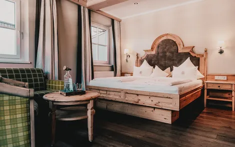 Cozy alpine hotel room with rustic wooden bed, green armchairs and elegant decor
