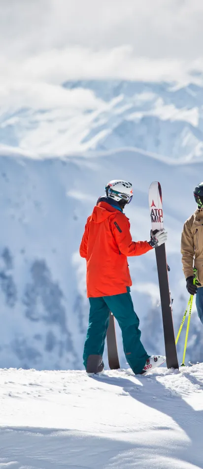 Gruppe von Skifahrern gibt sich High-Five auf schneebedecktem Berggipfel mit Alpenpanorama