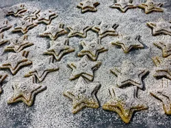 Star-shaped Christmas cookies dusted with powdered sugar on baking tray