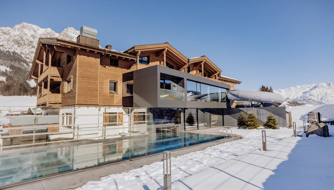 Luxury mountain hotel with outdoor pool in snowy alpine landscape