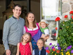 Smiling family in traditional clothing in front of a hotel with colorful flowers