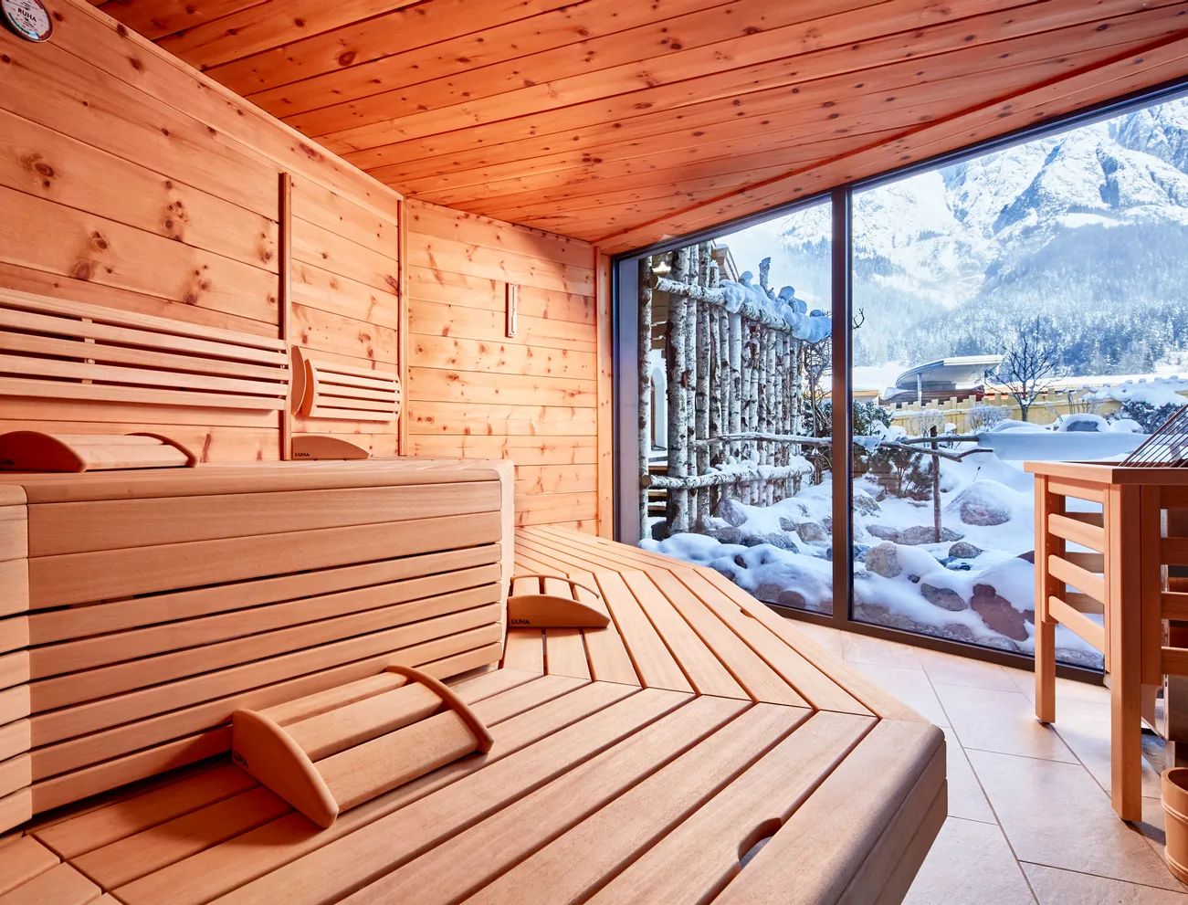 Holzsauna mit Panoramafenster und Blick auf verschneite Alpenberge