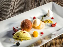 Gourmet-Dessert mit Schokoladenmousse, Eis, Früchten und Baiser auf weißem Teller