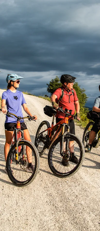 Group of cyclists on mountain trail enjoying scenic landscape with cloudy sky