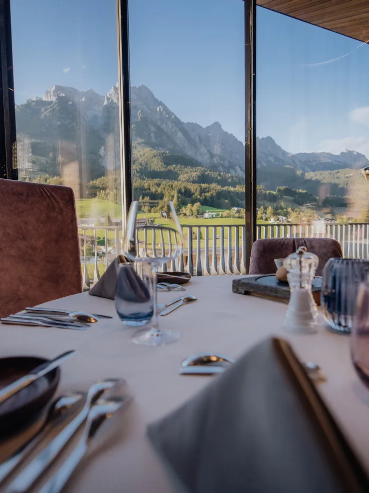 Elegant restaurant table setting with panoramic mountain view through large windows