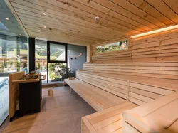 Moderne Innensauna aus Holz mit Bänken und Panoramablick auf die Berge