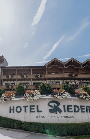 Hotel Riederalm in Leogang with alpine wooden architecture and flower-decorated balconies