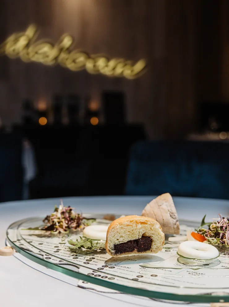 Gourmet dish with salad, bread and beer served on a modern glass plate at fine dining restaurant