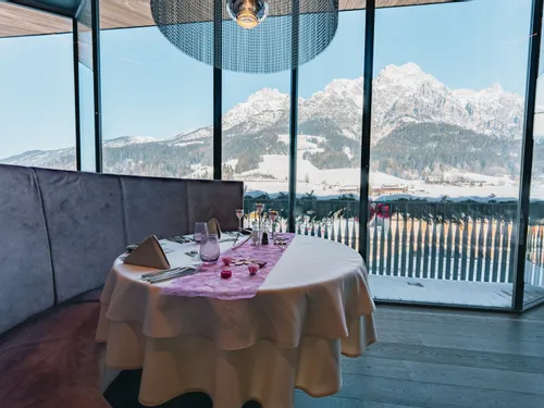Gedeckter Restauranttisch mit Panoramablick auf verschneite Alpenlandschaft