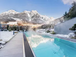 Heated outdoor pool in winter with snowy mountain view in alpine resort