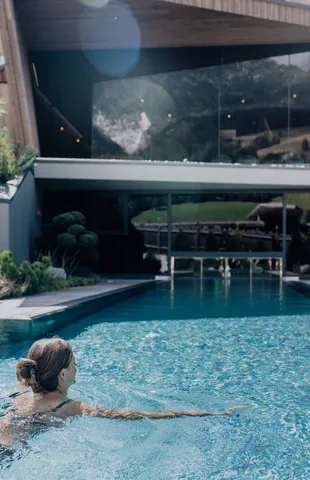 Frau schwimmt in einem luxuriösen Außenpool eines modernen Wellnesshotels