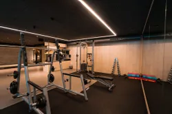 Moderner Fitnessraum mit Krafttrainingsgeräten, Hanteln und Gymnastikmatten
