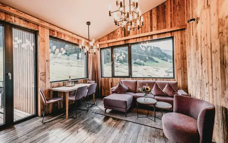 Cozy alpine vacation apartment living room with wood paneling and panoramic mountain view