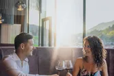 Couple enjoying romantic dinner with wine in elegant restaurant at sunset