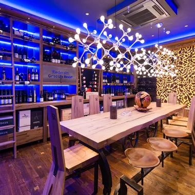 Modern wine cellar with wooden table, designer lighting and shelves of wine bottles