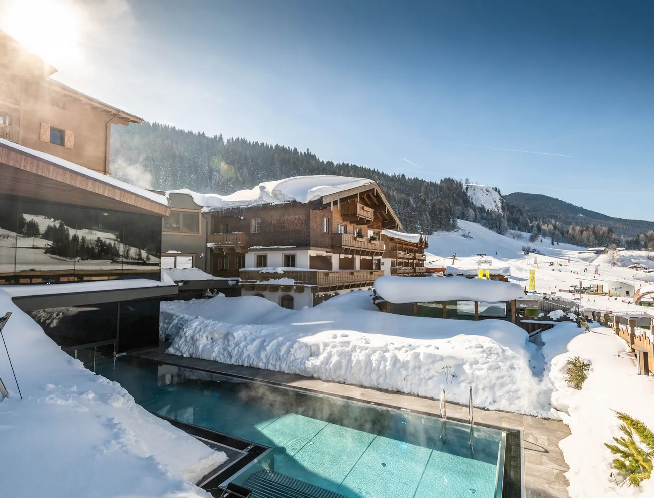 Luxuriöses Alpenresort mit beheiztem Außenpool umgeben von schneebedeckten Bergen