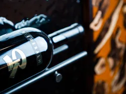 Riederalm-Weinflasche in einem Metall-Weinregal liegend