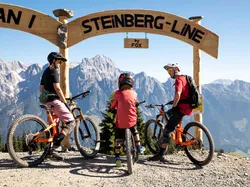 Familie mit Mountainbikes am Start der Steinberg Line mit Alpenpanorama im Hintergrund
