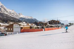 Skier approaching alpine resort Die Riederalm in snowy Leogang with mountain backdrop