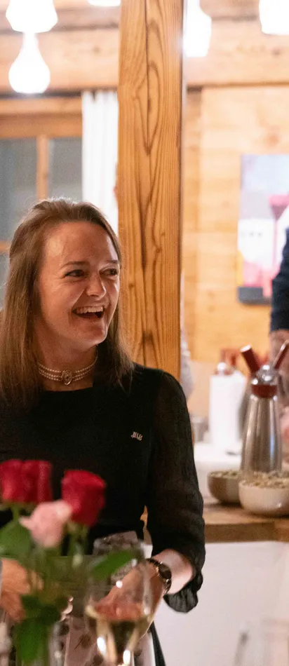 Drei Frauen lachen bei einem festlichen Abendessen in einem gemütlichen Holzrestaurant