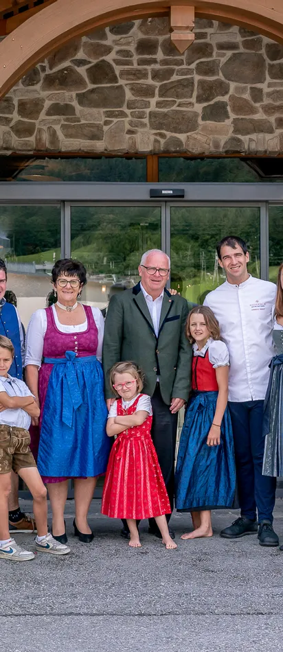 Familie in traditioneller Tracht vor Hotel mit Blumen und Steinfassade