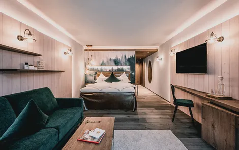 Modern hotel room with woodland-themed wall art, velvet sofa, and wooden furnishings