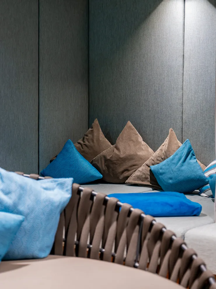 Cozy spa lounge with blue and brown pillows, soft lighting, and books on a wooden shelf