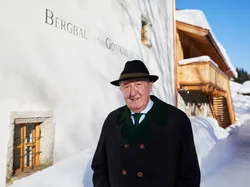 Älterer Mann im Wintermantel vor dem Bergbau- und Gotikmuseum in verschneitem Dorf