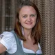 Woman in traditional Bavarian dirndl dress smiling in front of chain curtain