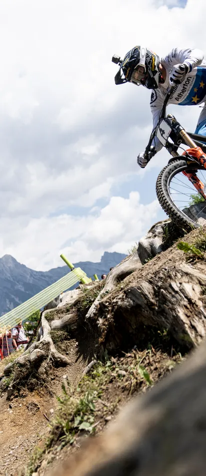 Mountain bike racer riding rocky trail during competition in the Alps with cheering spectators