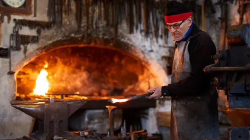 Schmied bearbeitet erhitztes Metall in traditioneller Schmiedewerkstatt