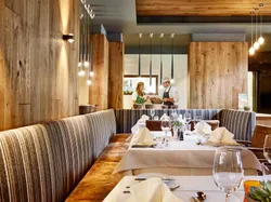 Elegant restaurant interior with set tables, wooden walls, and open kitchen in background