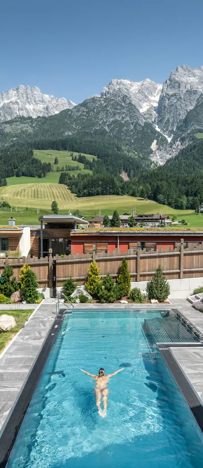 Mountain resort with outdoor pool, sun loungers, and scenic alpine landscape