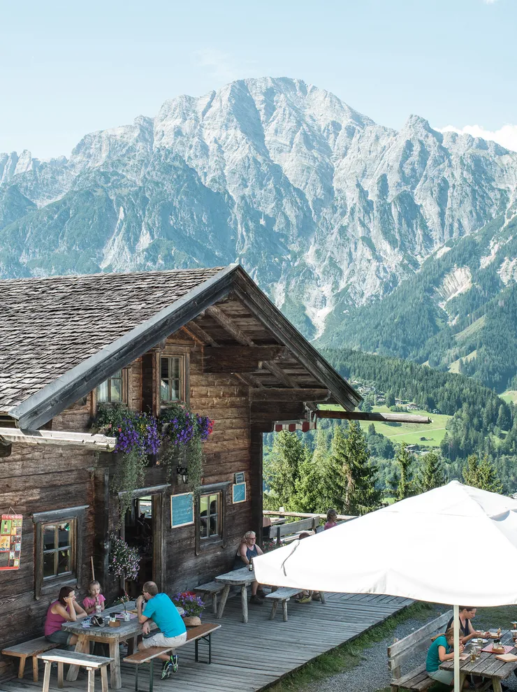 Alpine hut restaurant with outdoor seating overlooking scenic mountain landscape