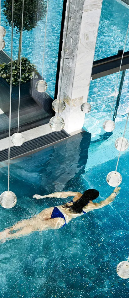 Woman swimming in a luxurious indoor spa pool with modern glass design