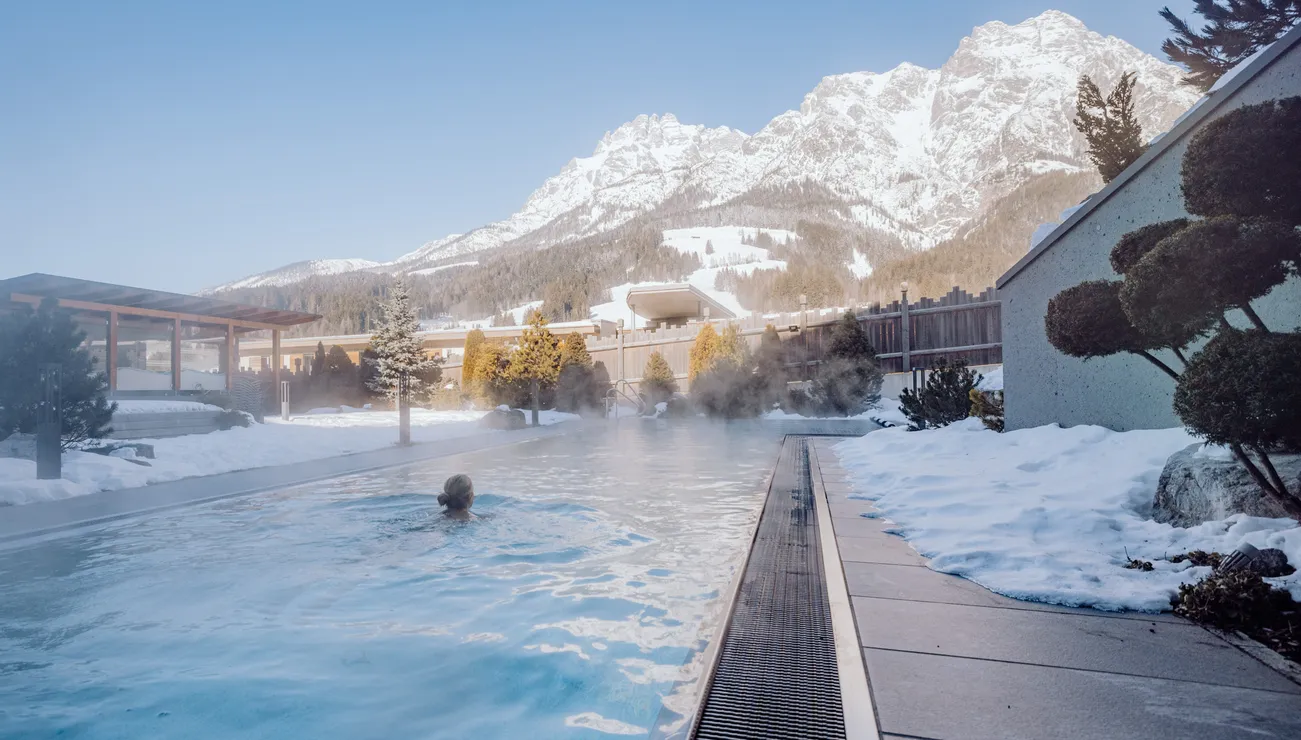 Outdoor thermal pool with mountain view and snow-covered surroundings in winter resort