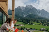 Couple in bathrobes enjoying mountain view from balcony in alpine resort