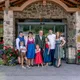 Family in traditional attire standing in front of hotel entrance with flowers and stone wall