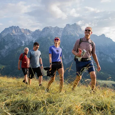 Group of hikers walking on a grassy trail with scenic mountain view in the background