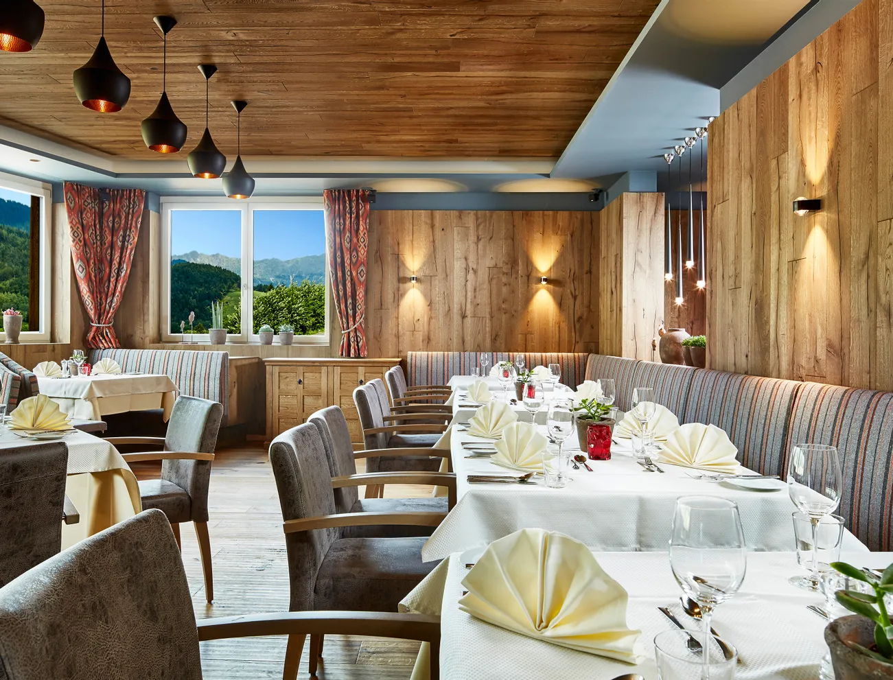 Elegantes Alpenrestaurant mit gefalteten Servietten, Holzdekor und Bergblick