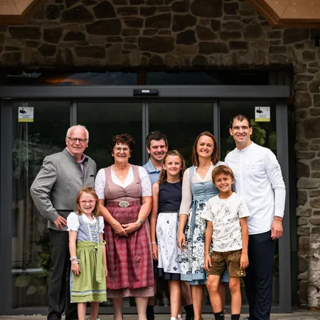 Multigenerational family posing in front of a wellness hotel with stone facade