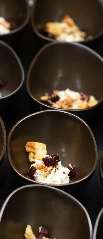 Kleine schwarze Schalen mit Gourmet-Dessert aus Sahne, Obst und Streuseln